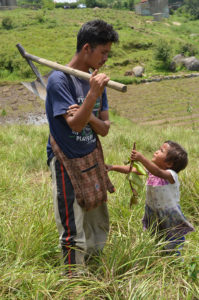 A farmer interacting with his daughter while she is holding a plant. Photo taken in Mawhiang, West Khasi Hills. 